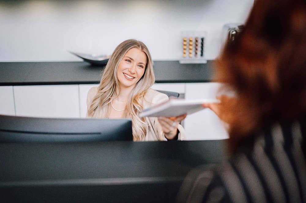 Eine Frau reicht einer anderen Frau Dokumente.