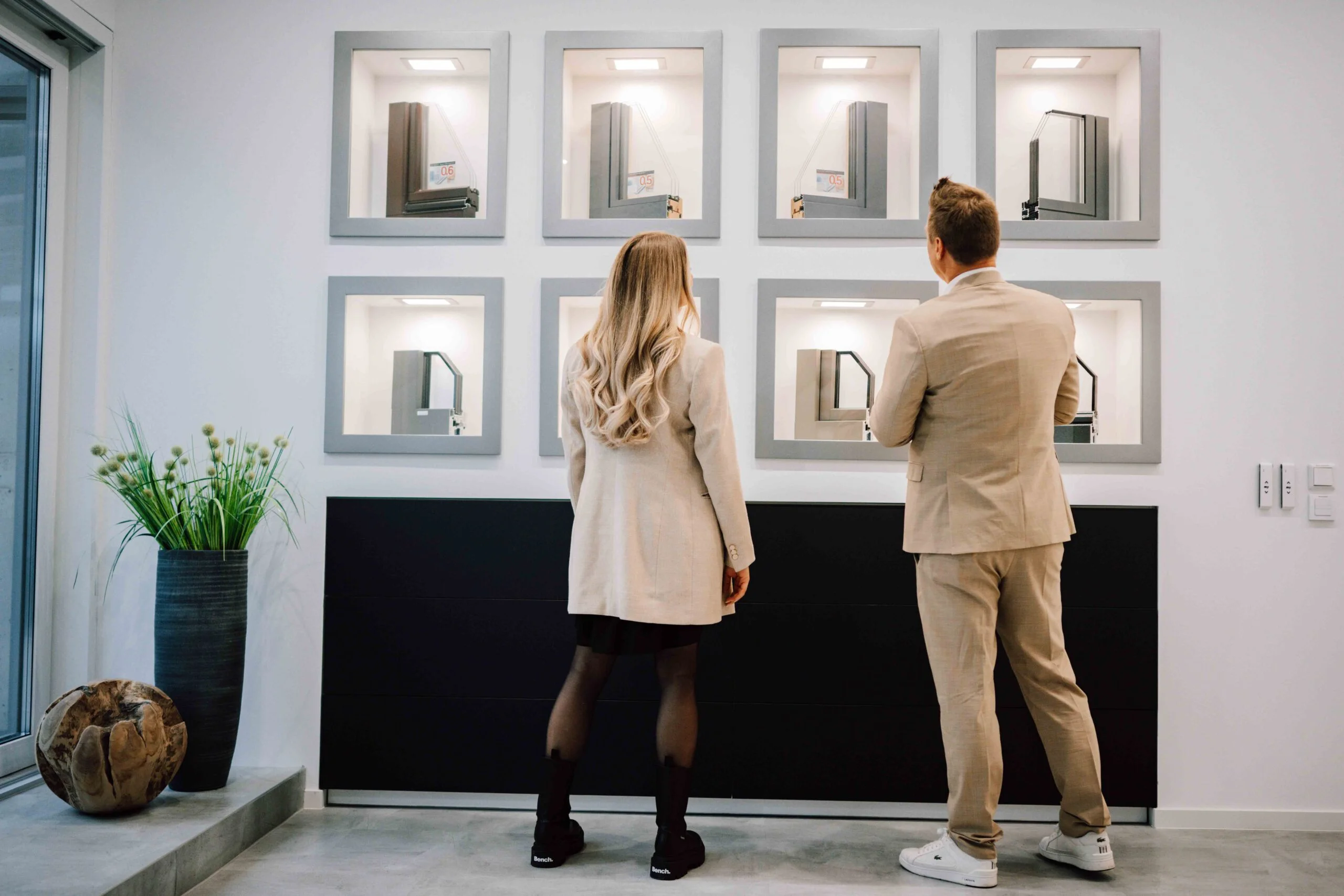 Ein Mann und eine Frau stehen vor einer Wand mit Fenstern in einem Showroom.