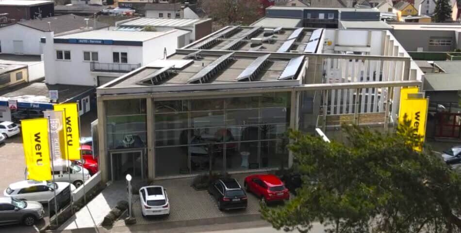 Ein großes Gebäude mit einem Weru-Schild und Autos auf dem Parkplatz.